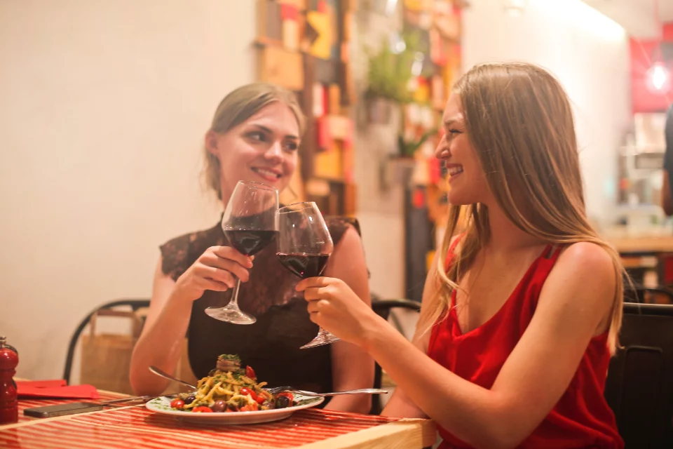 Deux amies dînant avec un verre de vin rouge